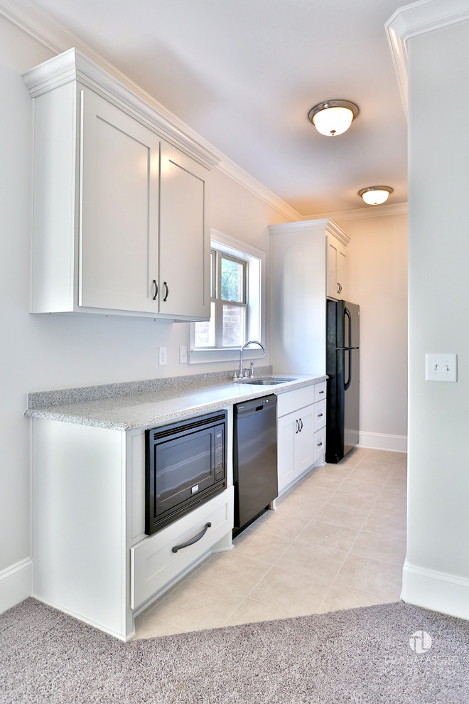 This is an example of a small traditional galley separate kitchen in Nashville with an undermount sink, shaker cabinets, white cabinets, laminate benchtops, black appliances, ceramic floors, no island and beige floor.