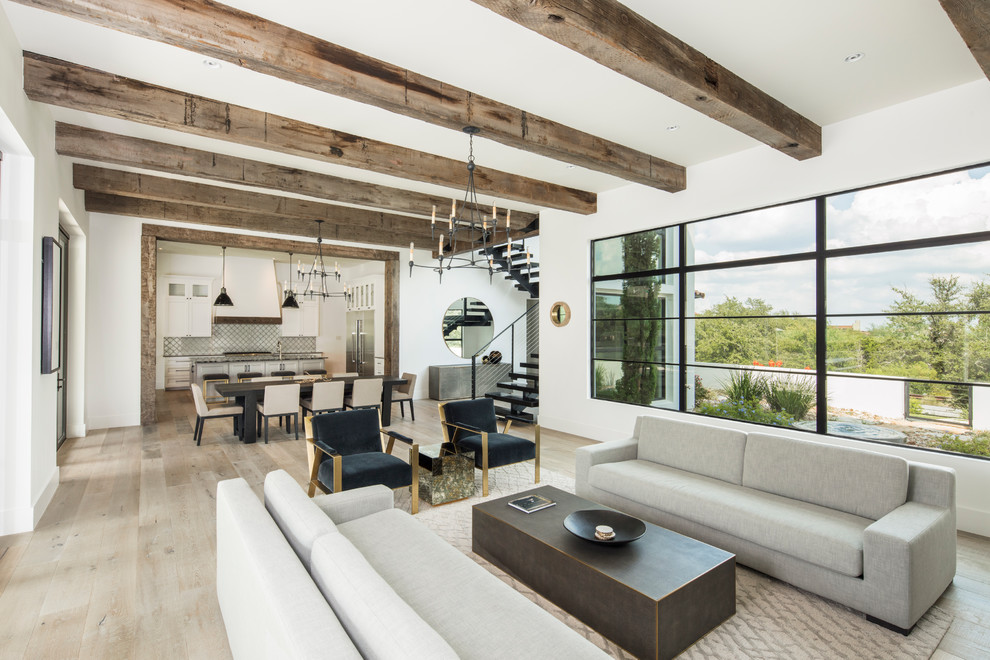 Photo of a contemporary open concept living room in Austin with white walls, light hardwood floors and beige floor.