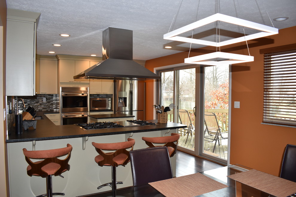 Inspiration for a transitional u-shaped laminate floor eat-in kitchen remodel with green cabinets, granite countertops, glass tile backsplash, stainless steel appliances and an island