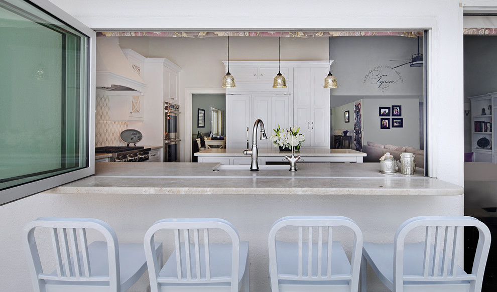 Mid-sized transitional u-shaped dark wood floor enclosed kitchen photo in Orange County with a farmhouse sink, beaded inset cabinets, white cabinets, quartzite countertops, white backsplash, glass sheet backsplash, stainless steel appliances and an island