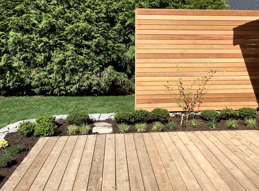This is an example of a mid-sized contemporary backyard partial sun garden in Vancouver with decking and with flowerbed.