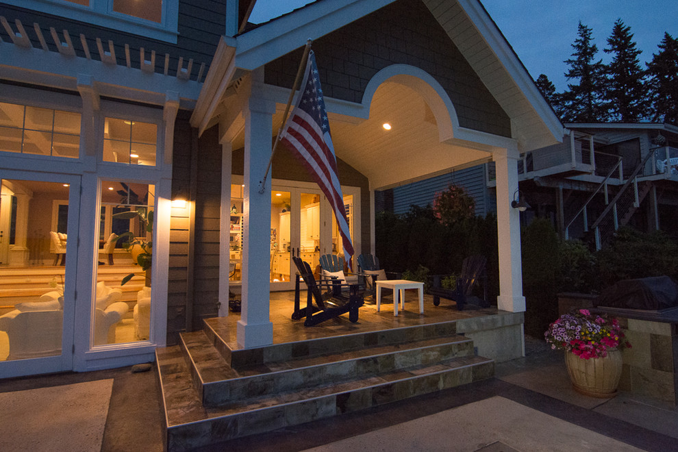 Beach style backyard patio in Seattle with an outdoor kitchen, natural stone pavers and a roof extension.
