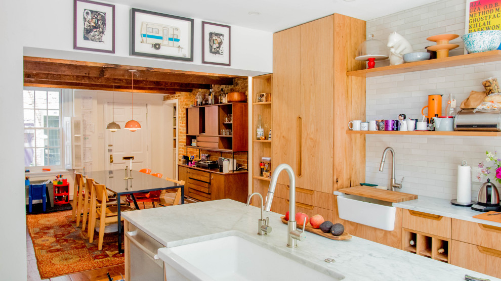 Photo of an eclectic kitchen in Philadelphia with a farmhouse sink, flat-panel cabinets, light wood cabinets, yellow splashback, panelled appliances, medium hardwood floors, with island, brown floor and yellow benchtop.