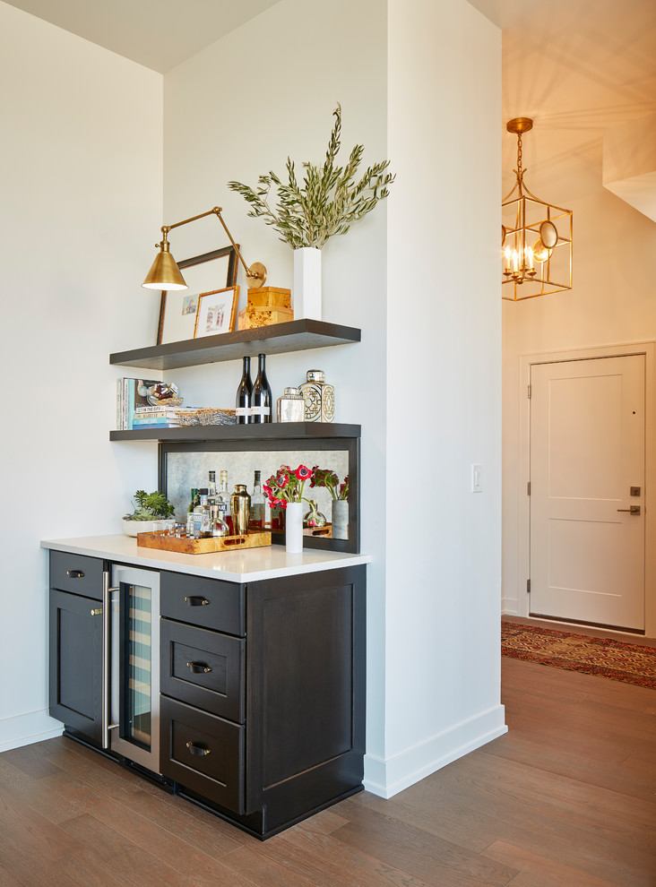 Mid-sized transitional single-wall wet bar in Chicago with recessed-panel cabinets, dark wood cabinets, quartz benchtops, grey splashback, mirror splashback, medium hardwood floors, grey floor and no sink.