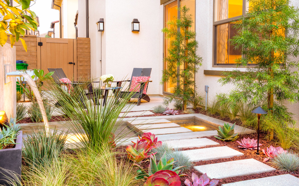 This is an example of a small modern side yard full sun garden in Orange County with a water feature and concrete pavers.