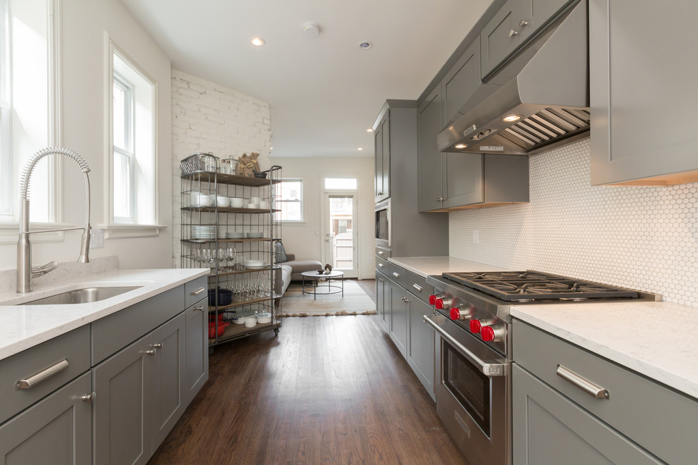Inspiration for a mid-sized country galley open plan kitchen in Dallas with an undermount sink, shaker cabinets, grey cabinets, quartz benchtops, white splashback, ceramic splashback, stainless steel appliances, medium hardwood floors and no island.