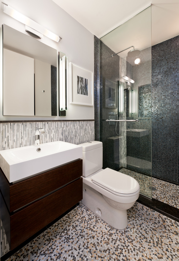 Photo of a small contemporary master bathroom in New York with a wall-mount sink, flat-panel cabinets, dark wood cabinets, an open shower, a one-piece toilet, black tile, mosaic tile, grey walls and marble floors.