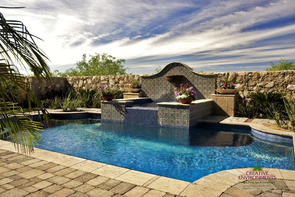 Hot tub - large backyard stamped concrete and custom-shaped hot tub idea in Phoenix