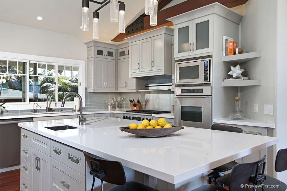 Mid-sized transitional u-shaped medium tone wood floor eat-in kitchen photo in San Diego with shaker cabinets, gray cabinets, gray backsplash, subway tile backsplash, stainless steel appliances, an island and an undermount sink