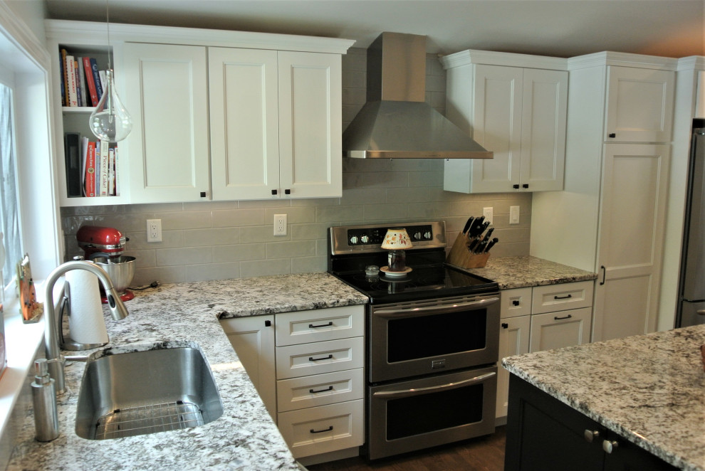 Transitional l-shaped medium tone wood floor and brown floor eat-in kitchen photo in Boston with an undermount sink, shaker cabinets, white cabinets, granite countertops, beige backsplash, subway tile backsplash, stainless steel appliances, an island and beige countertops