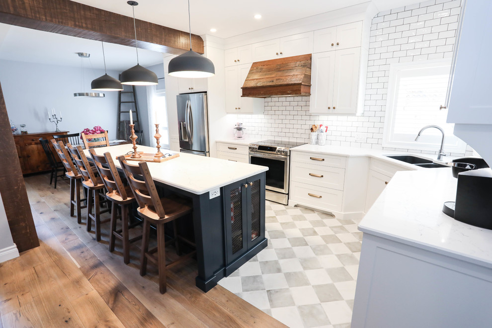 Inspiration for a large transitional l-shaped eat-in kitchen in Other with an undermount sink, shaker cabinets, white cabinets, quartz benchtops, white splashback, subway tile splashback, stainless steel appliances, porcelain floors, with island, beige floor and white benchtop.