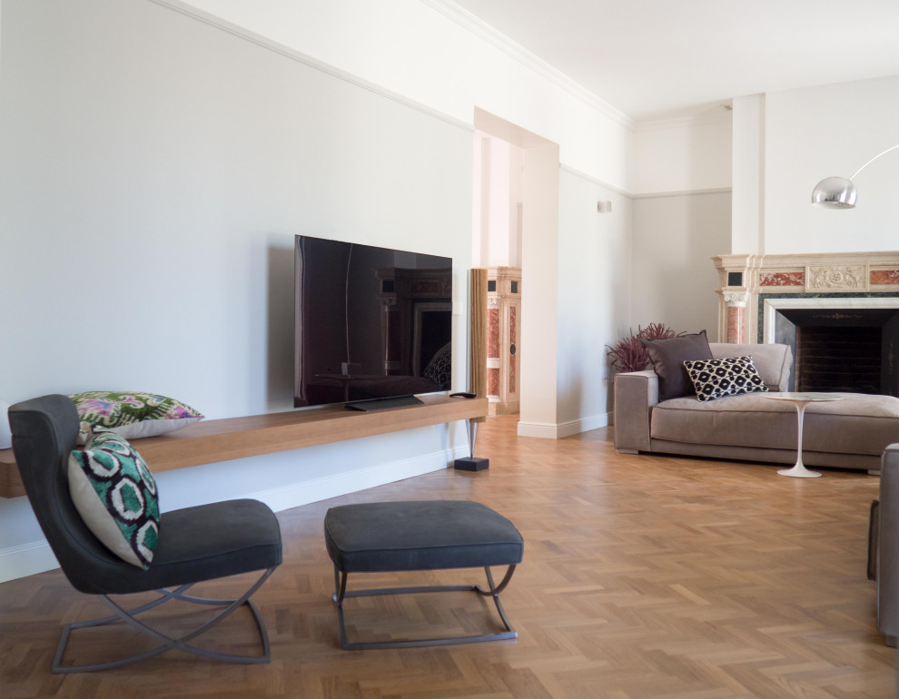 Стильный дизайн: большая открытая гостиная комната в современном стиле с серыми стенами, светлым паркетным полом, стандартным камином, фасадом камина из камня и телевизором на стене - последний тренд