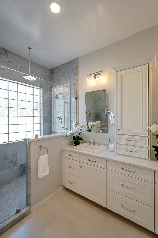 Large transitional master gray tile and marble tile porcelain tile and gray floor freestanding bathtub photo in Phoenix with recessed-panel cabinets, white cabinets, gray walls, a drop-in sink, quartz countertops and white countertops