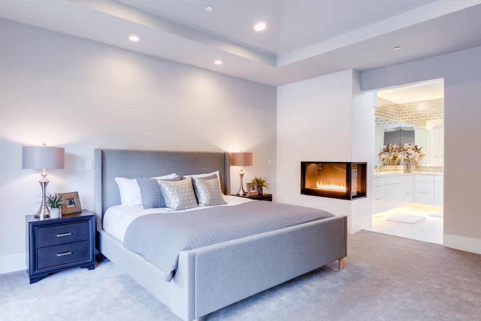 This is an example of a mid-sized modern master bedroom in Seattle with white walls, carpet, a corner fireplace, a tile fireplace surround and grey floor.