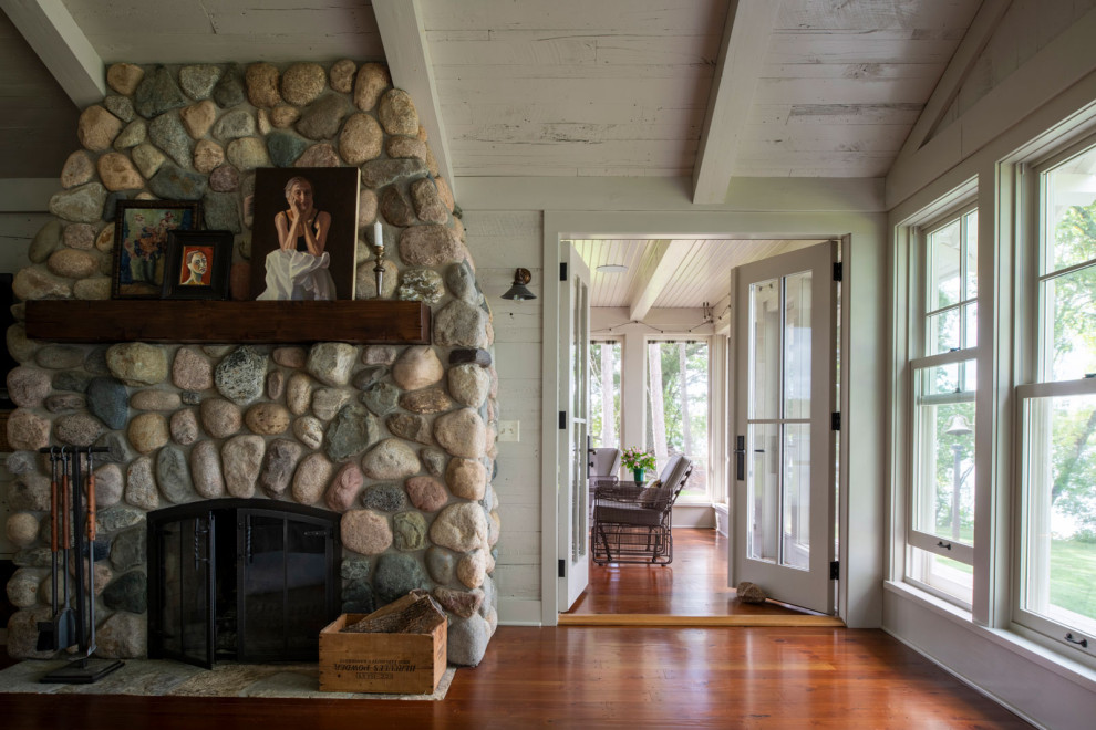 Foto de sala de estar abierta y abovedada costera de tamaño medio con suelo de madera en tonos medios, todas las chimeneas, marco de chimenea de piedra y madera