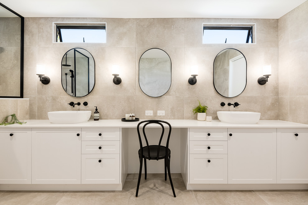 Inspiration for a large contemporary master bathroom in Brisbane with shaker cabinets, white cabinets, a drop-in tub, a double shower, a one-piece toilet, beige tile, porcelain tile, beige walls, porcelain floors, a console sink, solid surface benchtops, beige floor, an open shower and beige benchtops.