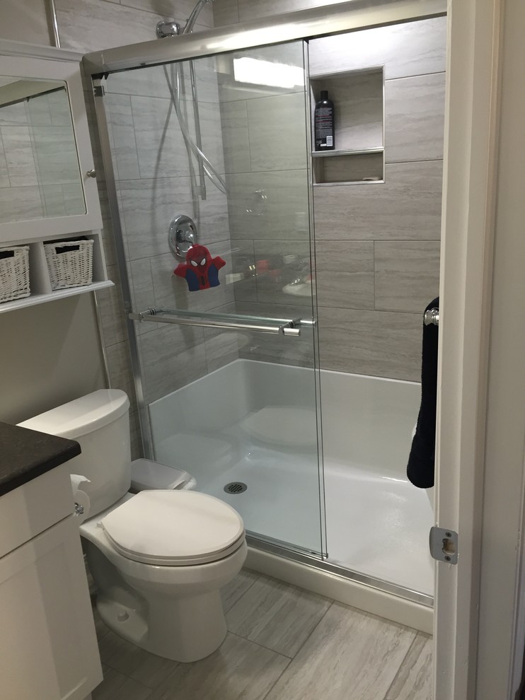 Inspiration for a mid-sized transitional 3/4 bathroom in Calgary with recessed-panel cabinets, yellow cabinets, an alcove shower, a two-piece toilet, gray tile, porcelain tile, grey walls and porcelain floors.