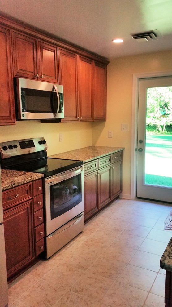 Example of a mid-sized transitional u-shaped porcelain tile eat-in kitchen design in DC Metro with an undermount sink, medium tone wood cabinets, granite countertops, stainless steel appliances and an island
