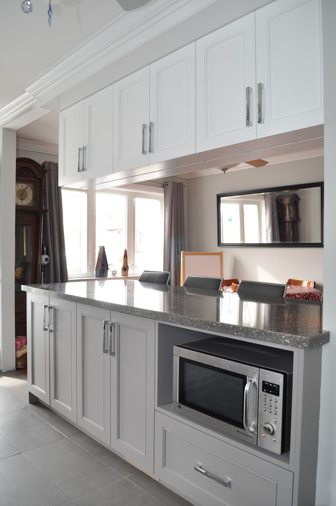 Example of a small transitional u-shaped porcelain tile and gray floor eat-in kitchen design in Toronto with an undermount sink, shaker cabinets, white cabinets, quartz countertops, white backsplash, porcelain backsplash, stainless steel appliances and an island