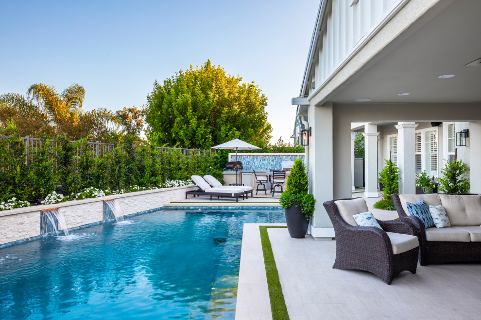 Modern rectangular pool in Orange County with a pool house and tile.