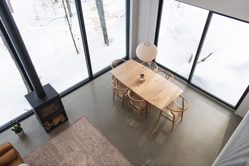 Exempel på en skandinavisk matplats, med vita väggar, betonggolv, en öppen vedspis och grått golv