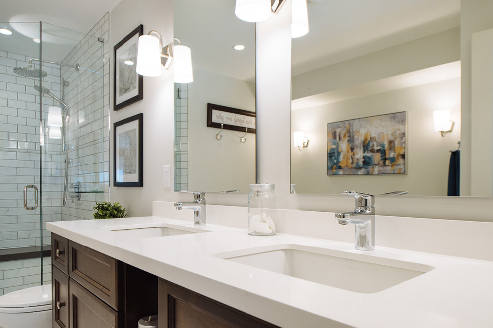 This is an example of a mid-sized country master bathroom in Vancouver with shaker cabinets, dark wood cabinets, a freestanding tub, a corner shower, a two-piece toilet, white tile, porcelain tile, white walls, porcelain floors, an undermount sink, engineered quartz benchtops, grey floor and a hinged shower door.