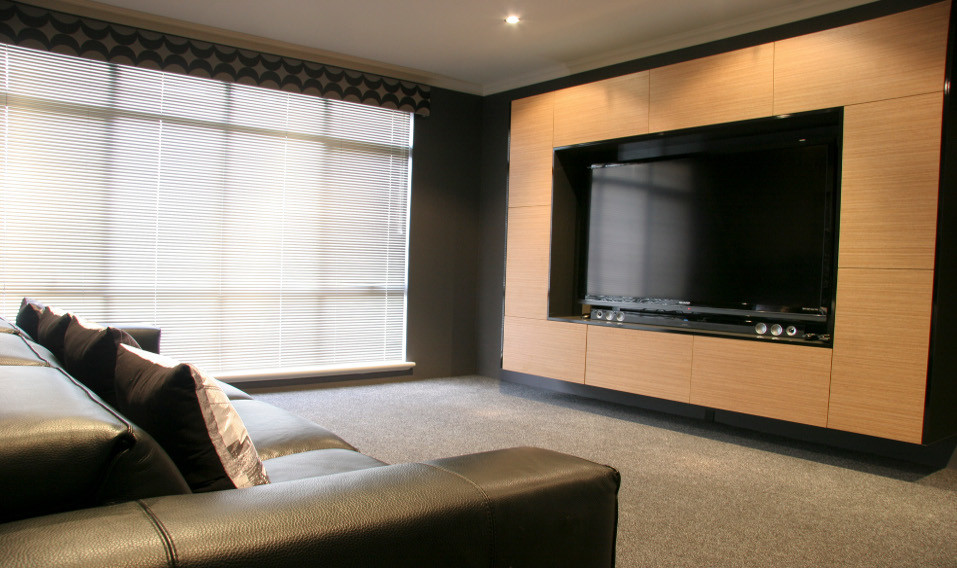 Photo of a mid-sized industrial enclosed home theatre in Perth with grey walls, carpet, a built-in media wall and grey floor.