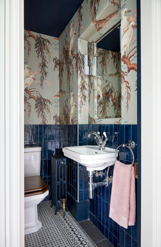 Small contemporary ensuite bathroom in London with a one-piece toilet, blue tiles, ceramic tiles, ceramic flooring, a wall-mounted sink and wallpapered walls.