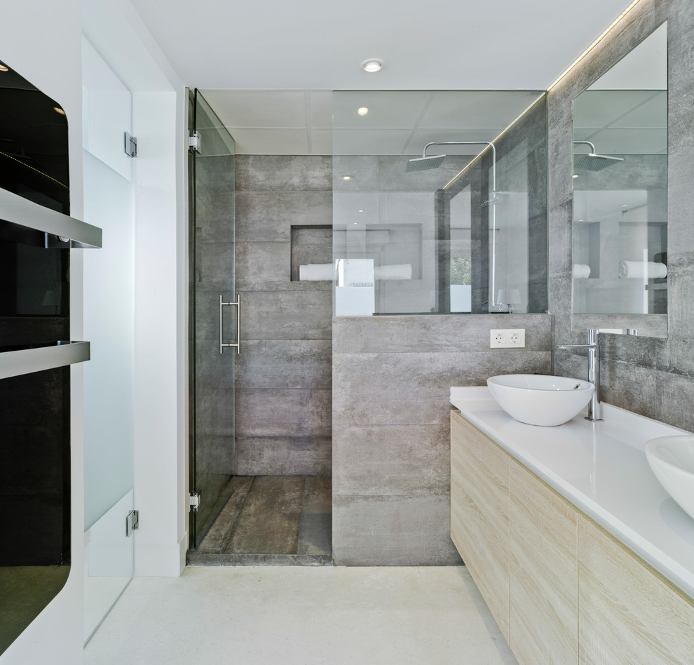 This is an example of a mid-sized contemporary bathroom in Other with flat-panel cabinets, light wood cabinets, white benchtops, an alcove shower, gray tile, cement tile, white walls, a vessel sink, a hinged shower door and beige floor.