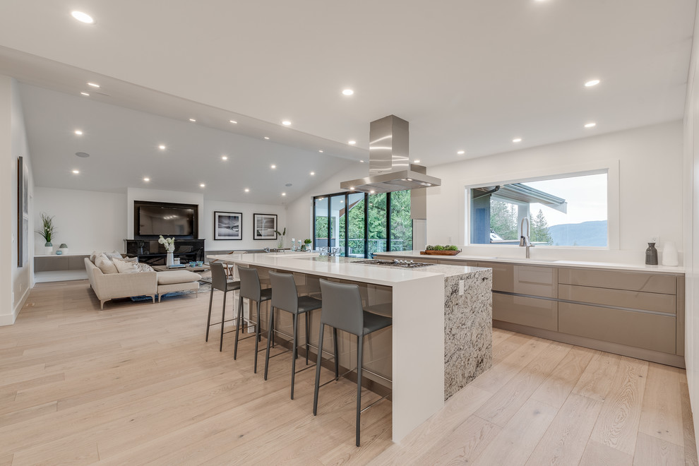 Design ideas for a modern open plan kitchen in Vancouver with an undermount sink, white cabinets, laminate benchtops, white splashback, stone slab splashback, stainless steel appliances, light hardwood floors, white benchtop and with island.