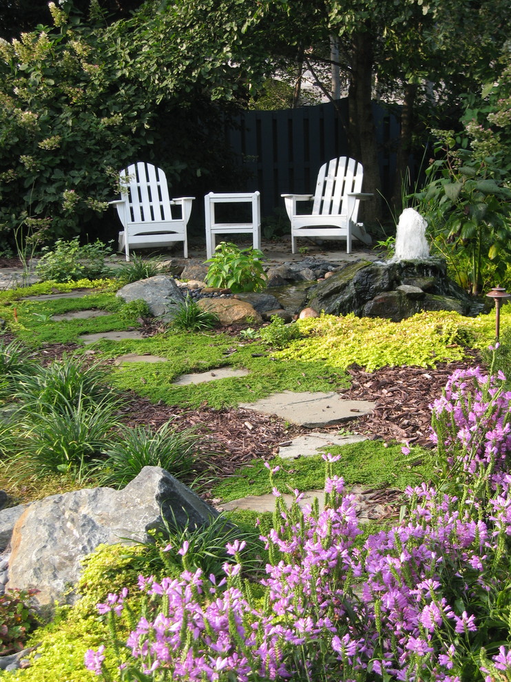 This is an example of an expansive eclectic backyard full sun garden for summer in Omaha with a water feature and mulch.