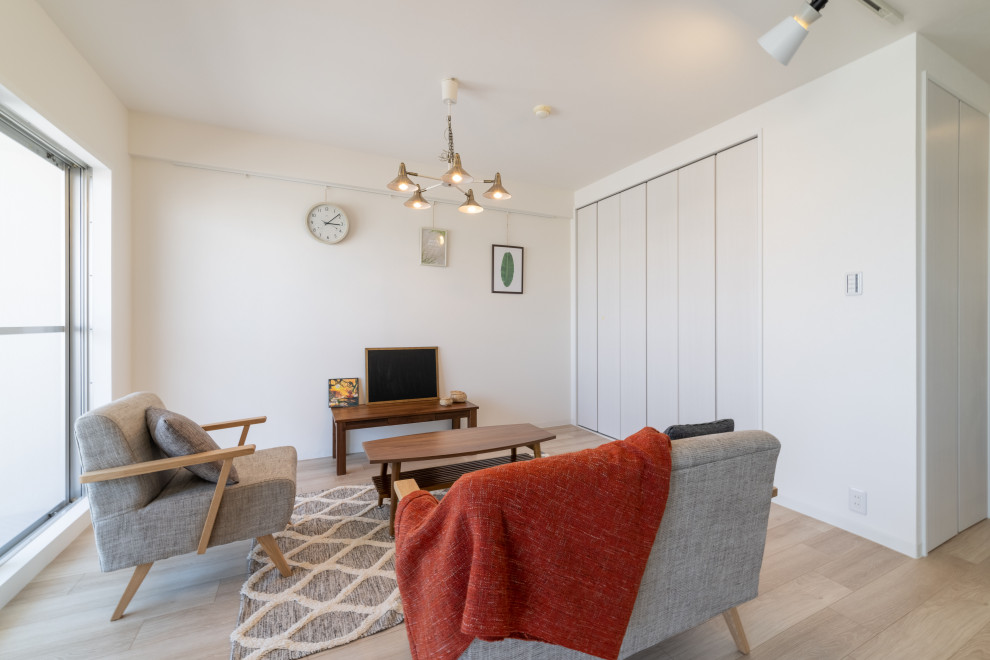 Kleines, Offenes Skandinavisches Wohnzimmer mit weißer Wandfarbe, gebeiztem Holzboden, freistehendem TV, beigem Boden, Tapetendecke und Tapetenwänden in Sonstige