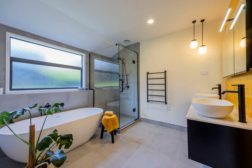 Foto på ett mellanstort funkis vit badrum för barn, med svarta skåp, ett fristående badkar, en hörndusch, gul kakel, keramikplattor, grå väggar, klinkergolv i porslin, ett fristående handfat, bänkskiva i kvarts, grått golv och dusch med gångjärnsdörr
