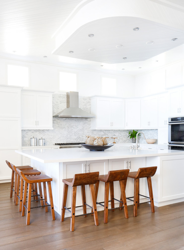 Open concept kitchen - large coastal l-shaped dark wood floor open concept kitchen idea in Orange County with a drop-in sink, shaker cabinets, white cabinets, quartz countertops, gray backsplash, mosaic tile backsplash, stainless steel appliances and an island