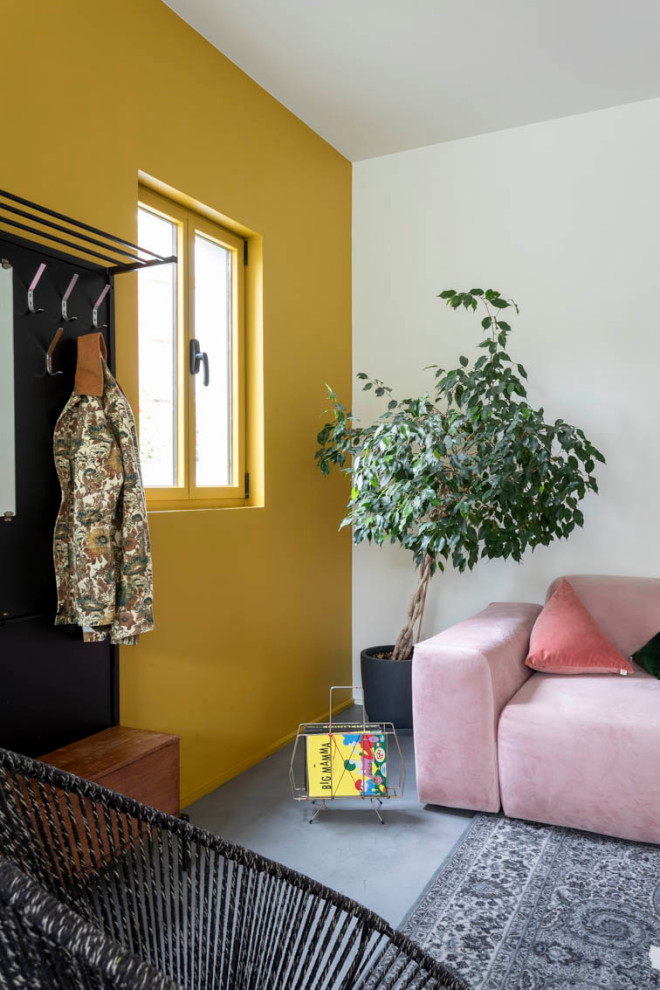 Aménagement d'un salon gris et jaune de taille moyenne et ouvert avec un mur blanc, sol en béton ciré, aucune cheminée, un téléviseur dissimulé, un sol gris et un escalier.