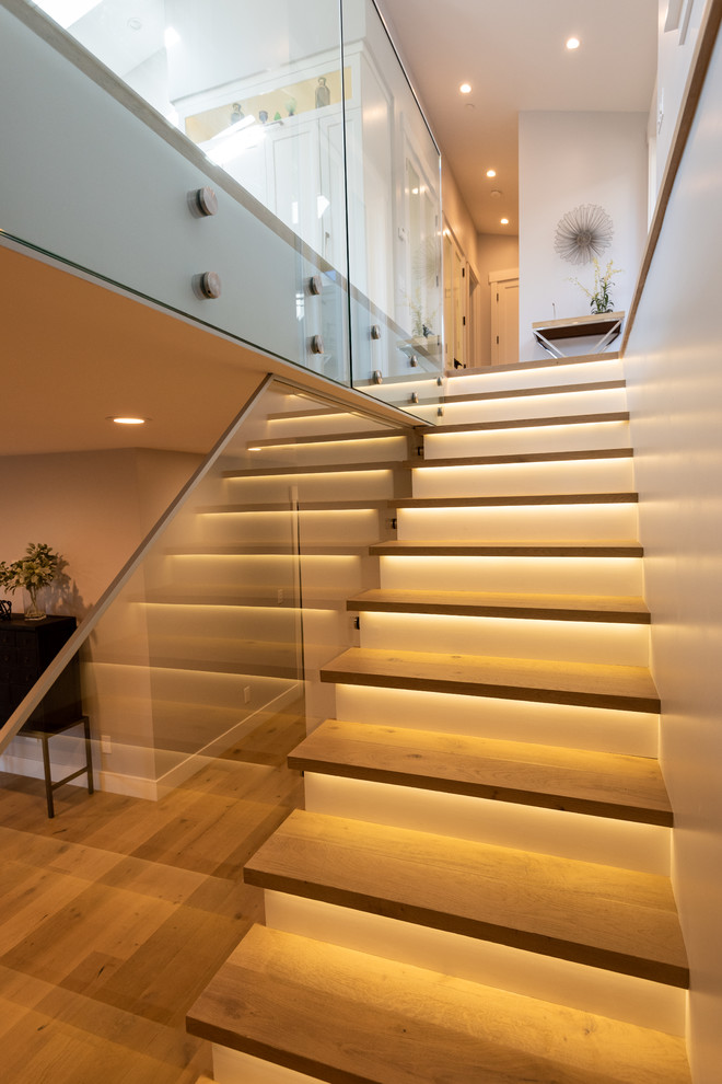 Photo of a mid-sized modern wood straight staircase in Other with wood risers and glass railing.