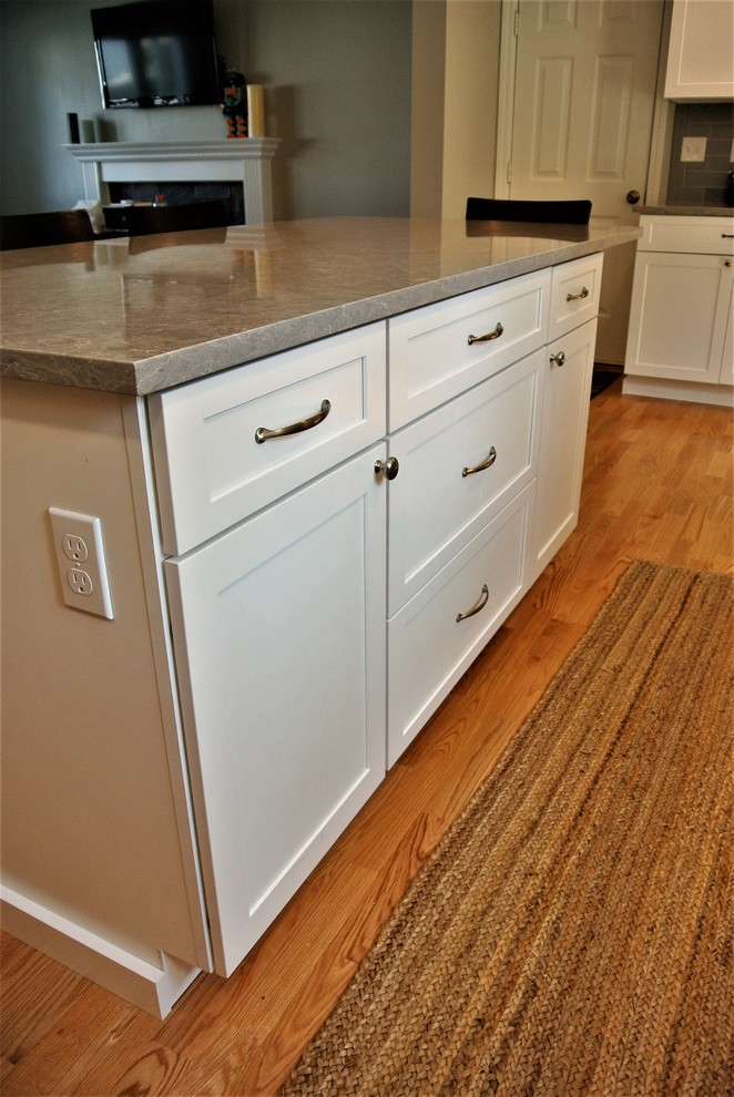 Kitchen - transitional light wood floor kitchen idea in Boston with an undermount sink, shaker cabinets, white cabinets, quartz countertops, gray backsplash, subway tile backsplash, stainless steel appliances, an island and gray countertops