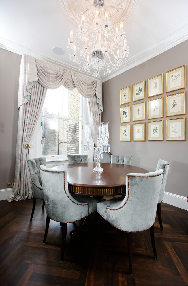 This is an example of a traditional dining room in London with grey walls and dark hardwood floors.