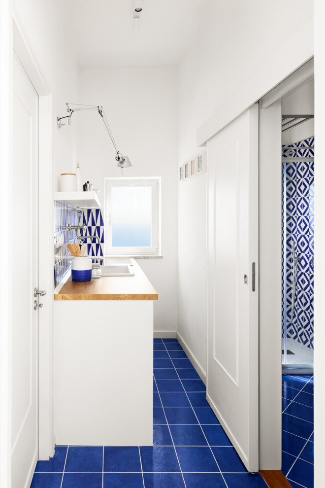 Источник вдохновения для домашнего уюта: маленькая прямая кухня-гостиная в средиземноморском стиле с одинарной мойкой, плоскими фасадами, белыми фасадами, деревянной столешницей, синим фартуком, фартуком из керамической плитки, белой техникой, полом из керамической плитки и синим полом для на участке и в саду