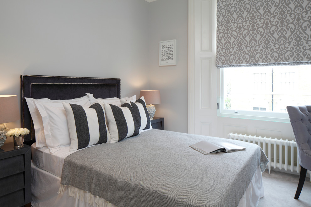 This is an example of a transitional guest bedroom in London with grey walls and carpet.