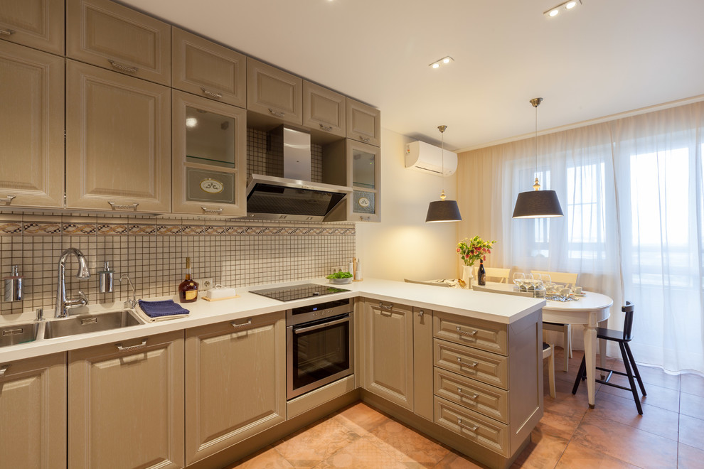 Inspiration for a mid-sized traditional l-shaped eat-in kitchen in Moscow with an undermount sink, recessed-panel cabinets, beige cabinets, solid surface benchtops, beige splashback, mosaic tile splashback, stainless steel appliances, ceramic floors and pink floor.