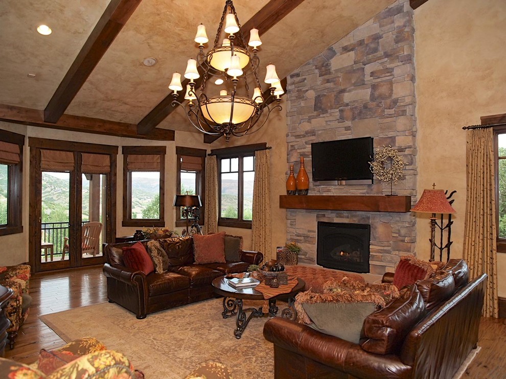 This is an example of an expansive country open concept family room in Salt Lake City with a game room, beige walls, light hardwood floors, a standard fireplace and a wall-mounted tv.