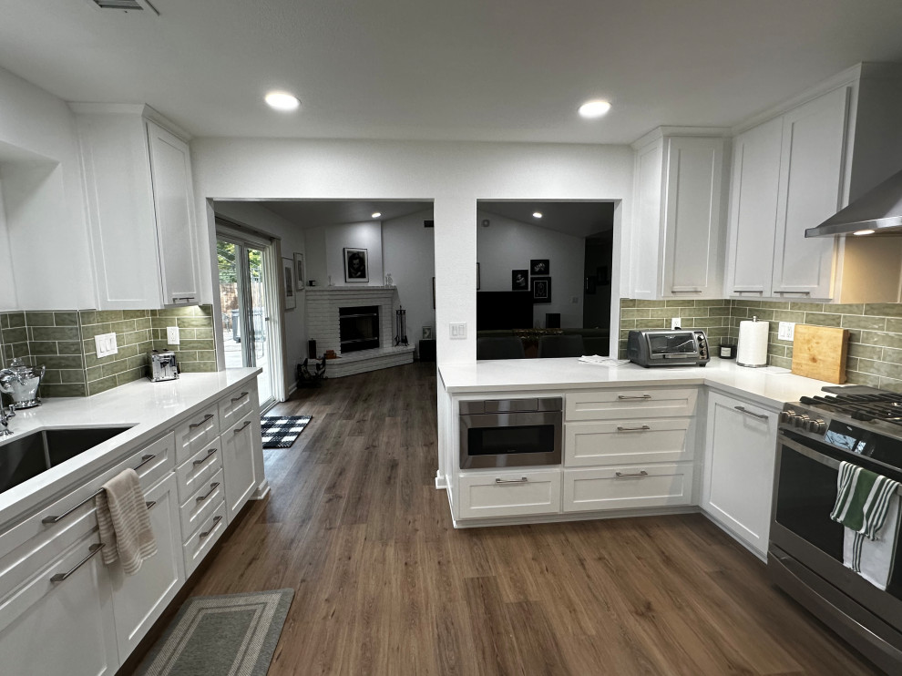 Exempel på ett mellanstort klassiskt vit vitt kök, med en enkel diskho, skåp i shakerstil, vita skåp, bänkskiva i kvarts, grönt stänkskydd, stänkskydd i tunnelbanekakel, rostfria vitvaror, en halv köksö och brunt golv