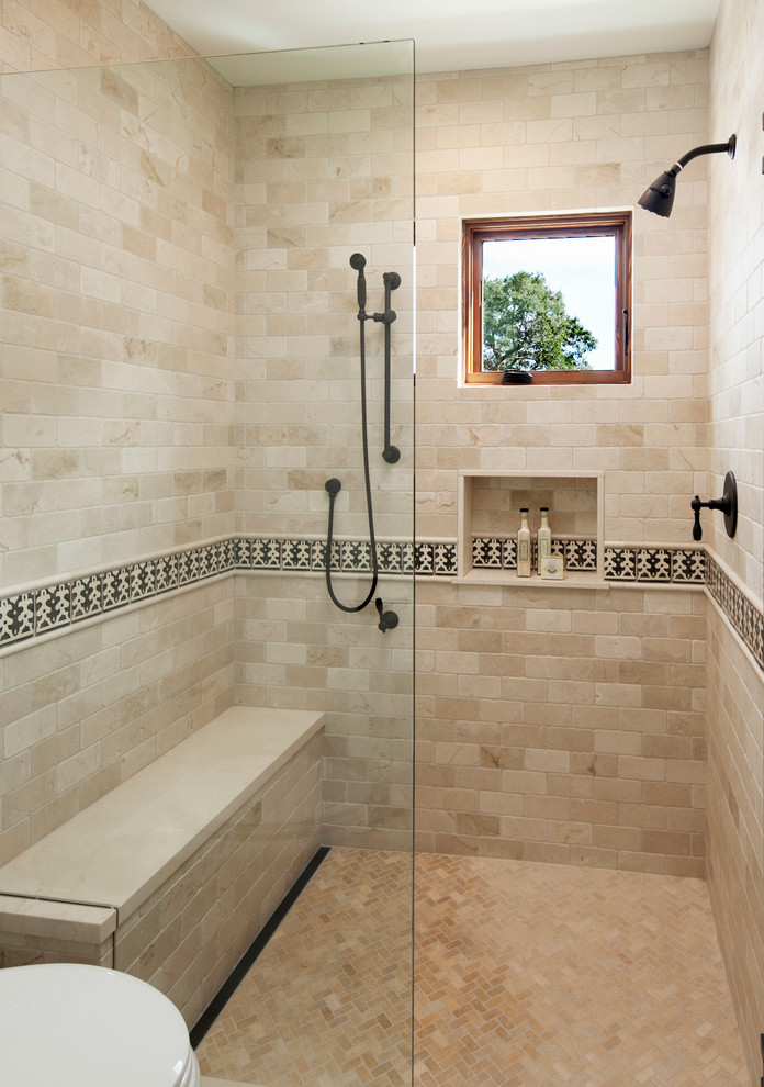 Mid-sized mediterranean bathroom in Santa Barbara with an undermount sink, recessed-panel cabinets, medium wood cabinets, a curbless shower, a two-piece toilet, beige tile, stone tile and beige walls.