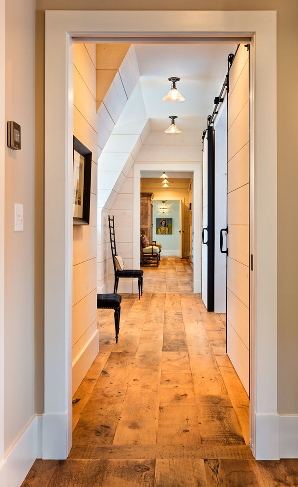 Design ideas for a mid-sized country hallway in Milwaukee with white walls, medium hardwood floors and brown floor.