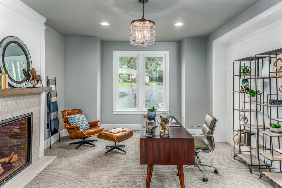 This is an example of a mid-sized transitional study room in Portland with grey walls, carpet, a standard fireplace, a tile fireplace surround, a freestanding desk and grey floor.