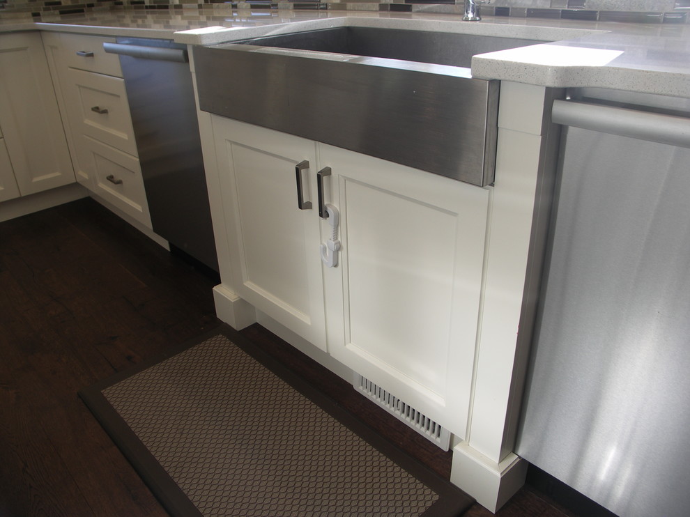 Inspiration for a transitional u-shaped medium tone wood floor kitchen remodel in Edmonton with a farmhouse sink, recessed-panel cabinets, white cabinets, glass tile backsplash, stainless steel appliances and an island