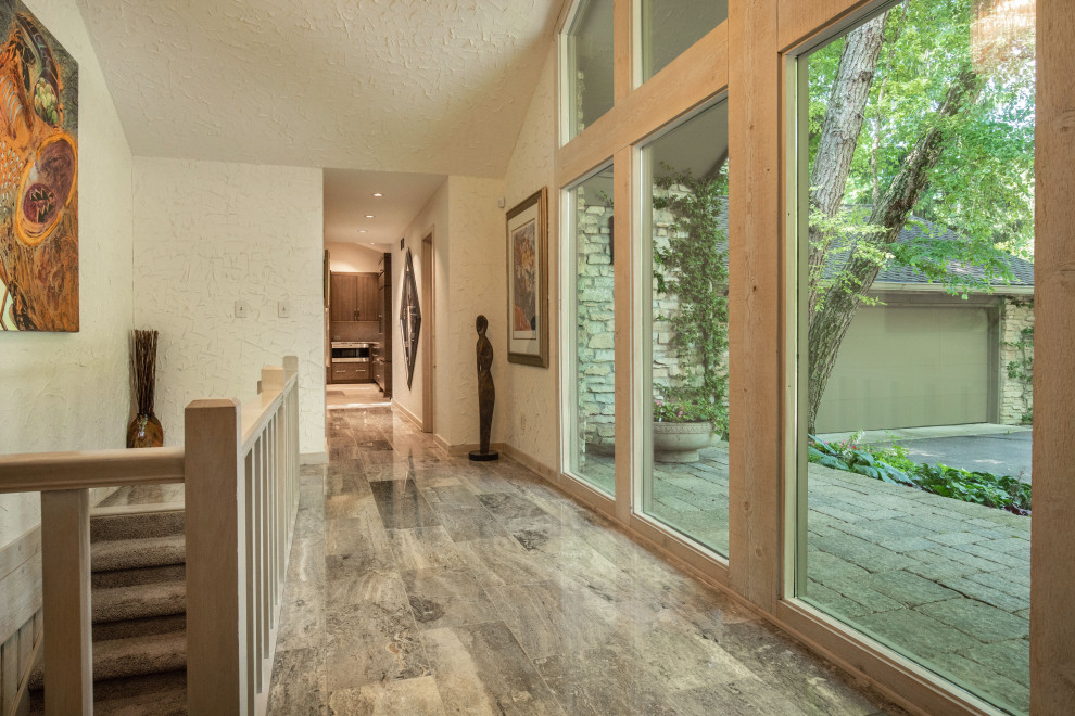 This is an example of a large contemporary hallway in Indianapolis with beige walls, porcelain floors and beige floor.
