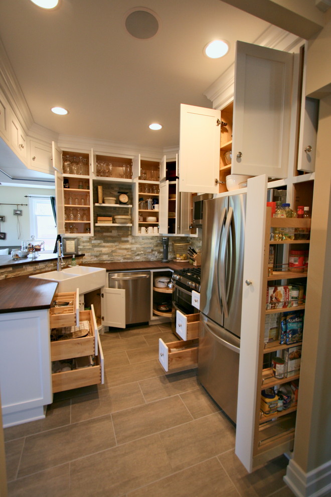 Inspiration for a timeless u-shaped eat-in kitchen remodel in Cincinnati with a farmhouse sink, flat-panel cabinets, white cabinets, wood countertops, multicolored backsplash, stone tile backsplash and stainless steel appliances