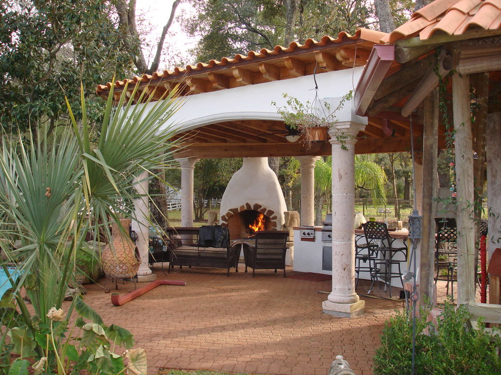 This is an example of a mediterranean backyard patio in Houston with a fire feature and brick pavers.